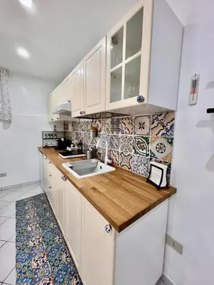 a kitchen with white cabinets and a wooden counter top at Scala Dei Normanni in Palermo