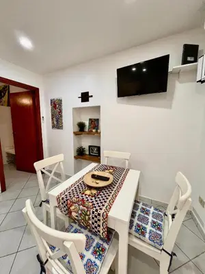a table and chairs with a table and a television on the wall at Scala Dei Normanni in Palermo