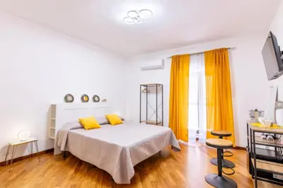 a white bedroom with a bed and yellow curtains at Balarm-Boutique Rooms in Palermo