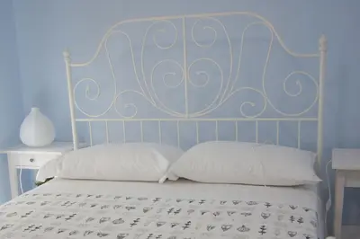 a bed with white pillows and a blue wall at Casa Oltremare UnmarediBlu in San Vito lo Capo