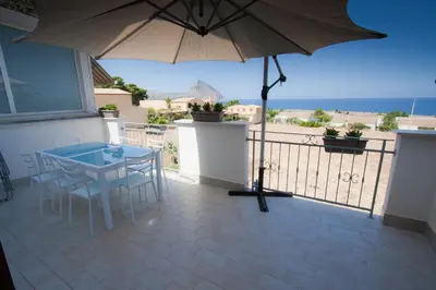 a balcony with an umbrella and a table and chairs at Casa Oltremare UnmarediBlu in San Vito lo Capo