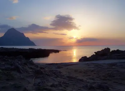 a sunset on a beach with the sun setting at Casa Oltremare UnmarediBlu in San Vito lo Capo