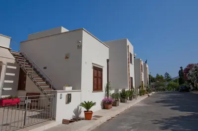 a row of white houses with potted plants on a street at Casa Oltremare UnmarediBlu in San Vito lo Capo