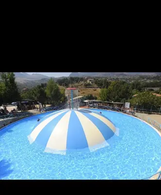 a large swimming pool with an umbrella in the water at Monreale Prestige Rooms B&B in Monreale