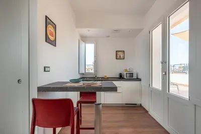 a kitchen with a counter and two red chairs at Candelai Apartments by Wonderful Italy in Palermo