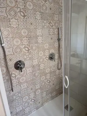 a shower with a glass door with a mosaic tile wall at Goodnight Palermo in Palermo