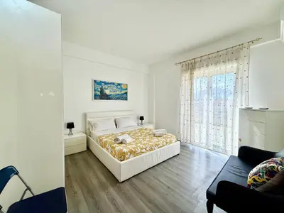 a white bedroom with a bed and a large window at La Coccola in Palermo