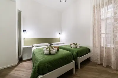 two beds in a white room with green sheets at Casa Mazzarino - Exclusive Vucciria Apartment in Palermo
