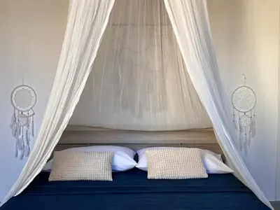 a bed with a canopy with two pillows at M'AMA apartment 3 in Ficarazzi