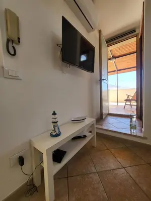 a room with a tv on a wall with a table at Le Case di Sole San Vito Lo Capo in San Vito lo Capo