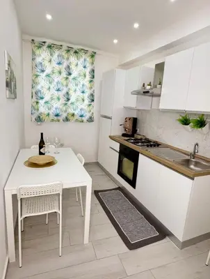 a white kitchen with a table and a sink at Ciuri D'Amuri in Palermo