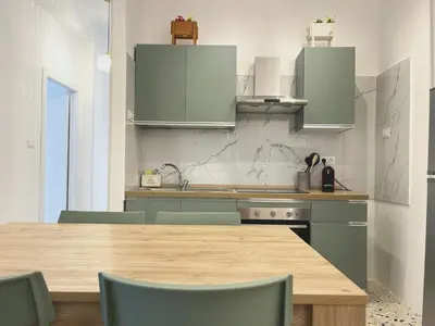 a kitchen with a wooden table and green chairs at Palermo central stay in Palermo