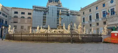 a fence in front of a building with a fountain at Al canto del sole in Palermo