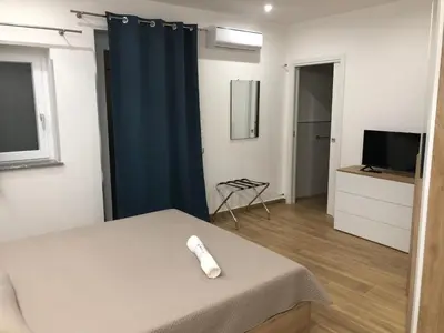 a room with a bed and a television and a chair at La Maison de Claude in Palermo