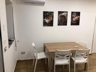 a dining room with a wooden table and white chairs at La Maison de Claude in Palermo