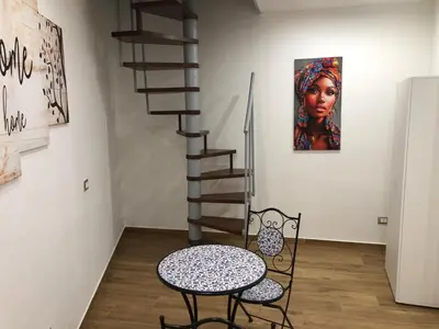 a table and chair in a room with a staircase at La Maison de Claude in Palermo