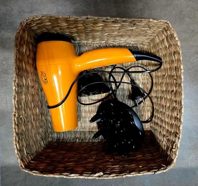 an orange blow dryer and a black object in a basket at DorMimmo a Palermo, nel cuore pulsante della città! in Palermo