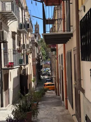 a narrow alley with a yellow car in the distance at Home Simo al Capo in the old center of Palermo in Palermo