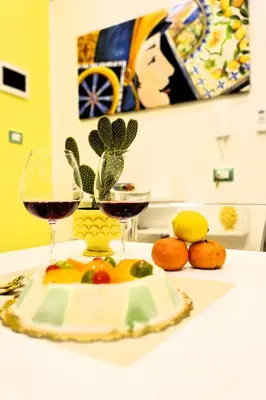 two glasses of wine and a plate of fruit on a table at Sikelia House - Comfort Apartment in Palermo