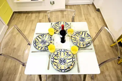 a white table with plates and a bottle of wine at Sikelia House - Comfort Apartment in Palermo