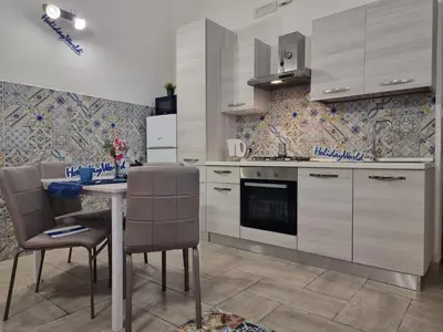 a kitchen with white cabinets and a table and chairs at Casa Vulpi by Holiday World in Palermo