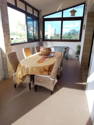a dining room with a table and chairs and windows at Casa del Sole in Campofelice di Roccella