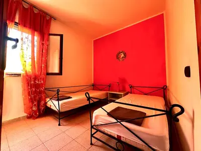 two beds in a room with a red wall at Casa del Sole in Campofelice di Roccella