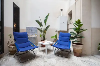 two blue chairs and a table in a room with plants at Cortile Galletti - Cool Flat with Private Courtyard in Palermo