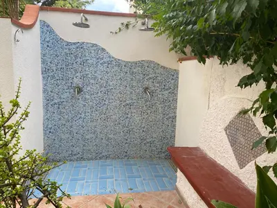 a shower with blue tiles on the side of a building at Villa Glicine a pochi passi dal mare e dal centro in San Vito lo Capo