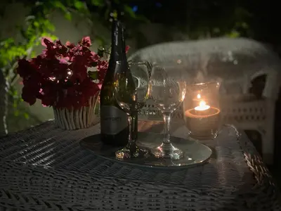 a bottle of wine and two glasses on a table with a candle at Villa Glicine a pochi passi dal mare e dal centro in San Vito lo Capo