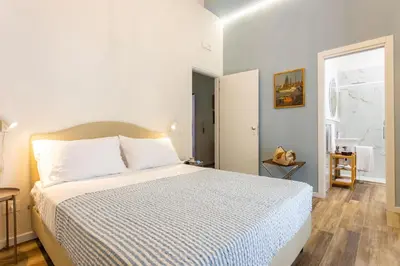 a bedroom with a large bed with white sheets and a window at Pagano Home Guesthouse in Palermo