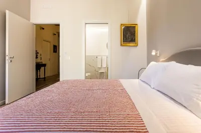 a bedroom with a large white bed and a mirror at Pagano Home Guesthouse in Palermo