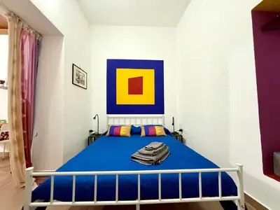 a bedroom with a blue bed and a painting on the wall at Vicolo Giardi in Palermo