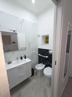 a white bathroom with a toilet and a sink at Trasi E Niesci Flat in Palermo