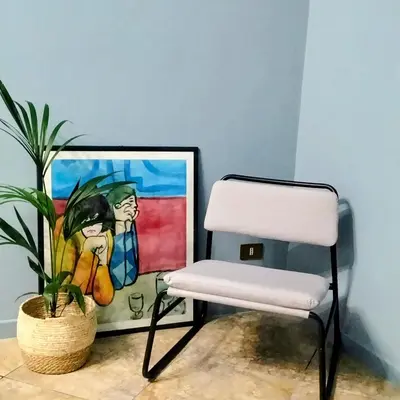 a white chair and a plant in front of a painting at BallarHòme 105 