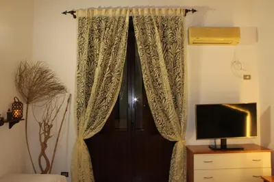 a door with a curtain next to a television at Giacalone15 - EXCLUSIVE APARTMENT IN THE HISTORIC CENTER NEAR THE TEATRO MASSIMO in Palermo