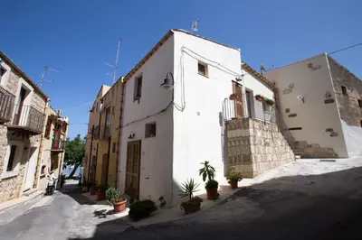 a white building with potted plants on a street at La Casetta nel Porto in Castellammare del Golfo