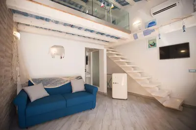 a living room with a blue couch and stairs at La Casetta nel Porto in Castellammare del Golfo