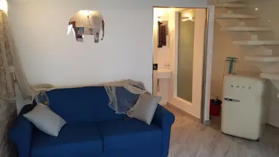 a blue couch in a living room with a staircase at La Casetta nel Porto in Castellammare del Golfo