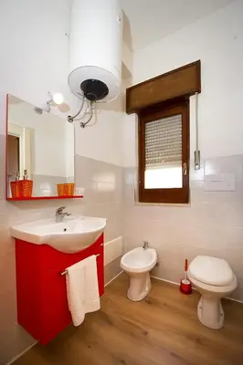 a bathroom with a red sink and a toilet at Affittacamere le scale in Castellammare del Golfo