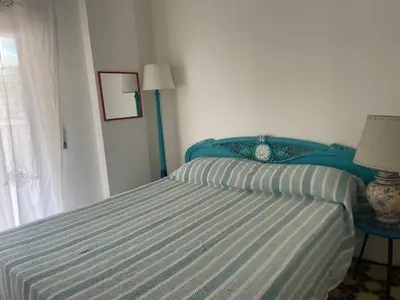 a bedroom with a bed with a blue headboard and a window at Casa del Sorriso in Isola delle Femmine