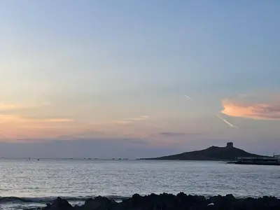 a sunset over the ocean with a hill in the distance at Casa del Sorriso in Isola delle Femmine