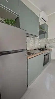 a kitchen with white cabinets and a refrigerator at Casetta Giardinetto in Altavilla Milicia