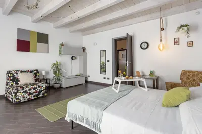 a white bedroom with a large bed and a chair at Mama apt - Comfort & style in Partanna Mondello in Palermo