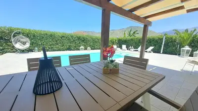 a wooden table with flowers and a swimming pool at Villa Elios Adriana2 in Lascari