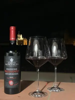 two glasses of red wine next to a bottle of wine at Dimora Stella Boutique in Alcamo