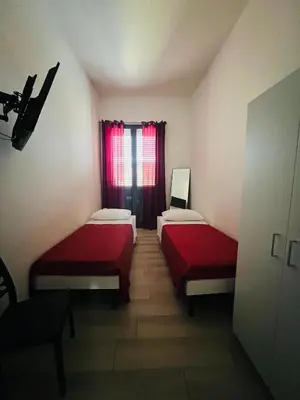 a room with two beds and a window with red curtains at AL CAPO casa vacanze in Palermo