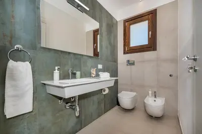 a bathroom with a sink and a toilet and a mirror at Villa Maria con piscina e vista mare 12 posti letto in Castellammare del Golfo