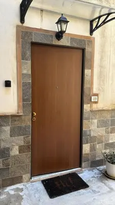 a brown door in a stone wall with a lamp at Casa AG in Palermo