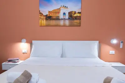 a bedroom with a white bed and a painting on the wall at Duecento Rooms in Palermo